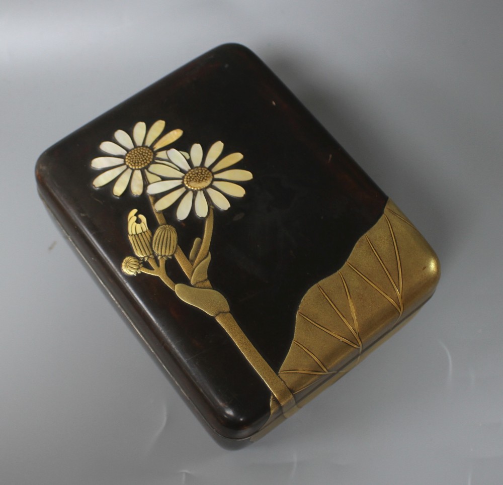 A Japanese Meiji period lacquer box, decorated with lotus leaves and flowers, with the petals inset with mother of pearl, silver rim an